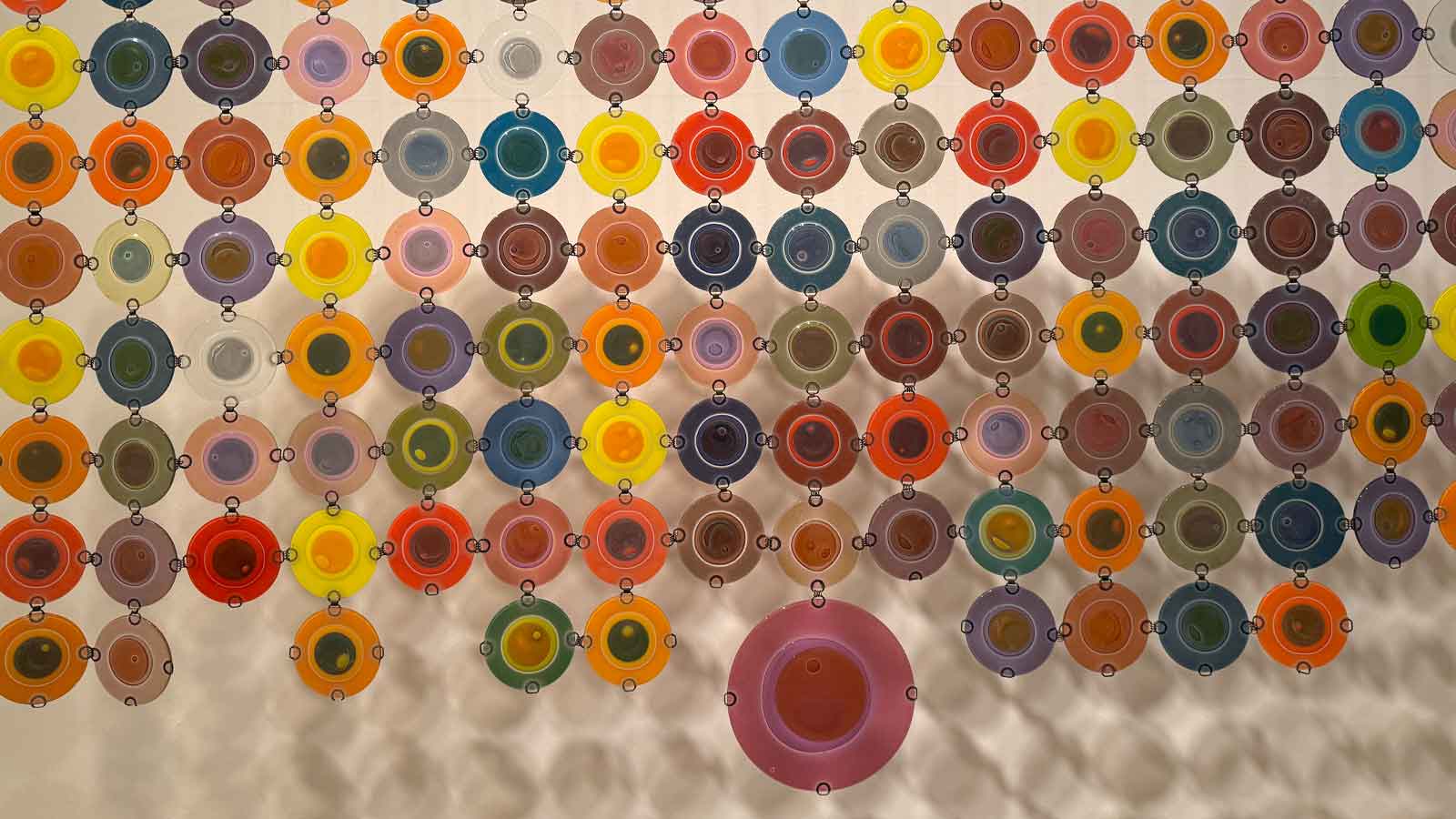 Translucent, multicolored discs arranged in a grid pattern, casting light and shadows